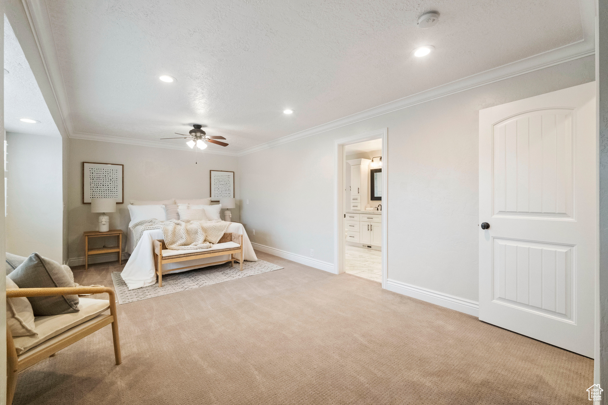 Bedroom with ceiling fan, ornamental molding, light carpet, and ensuite bath