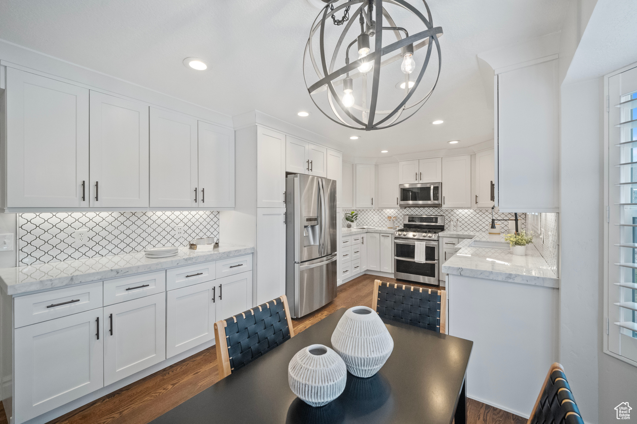 Kitchen featuring white cabinetry, hanging light fixtures, stainless steel appliances, and an inviting chandelier