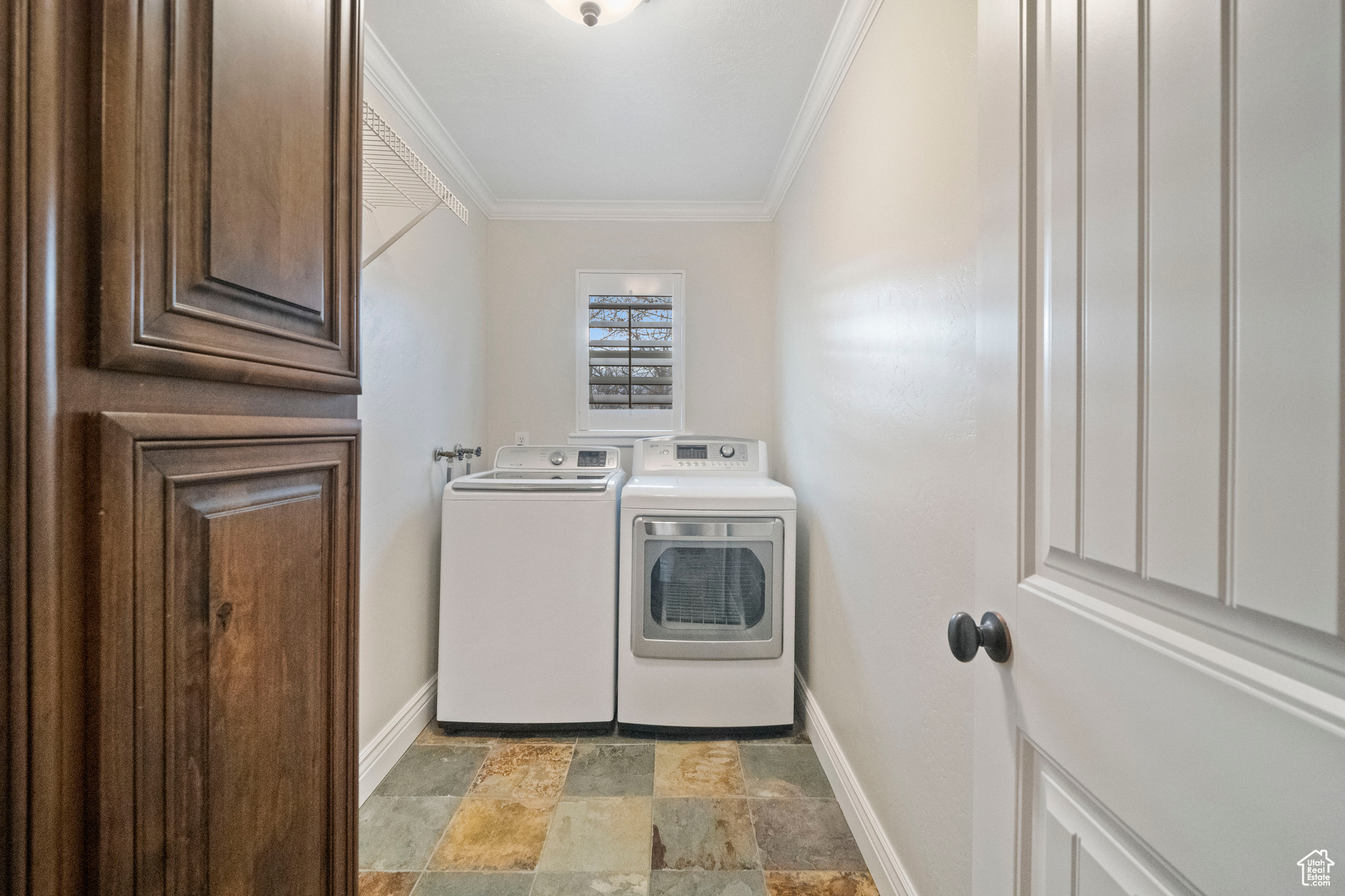 Washroom with cabinets, washer and dryer, and ornamental molding