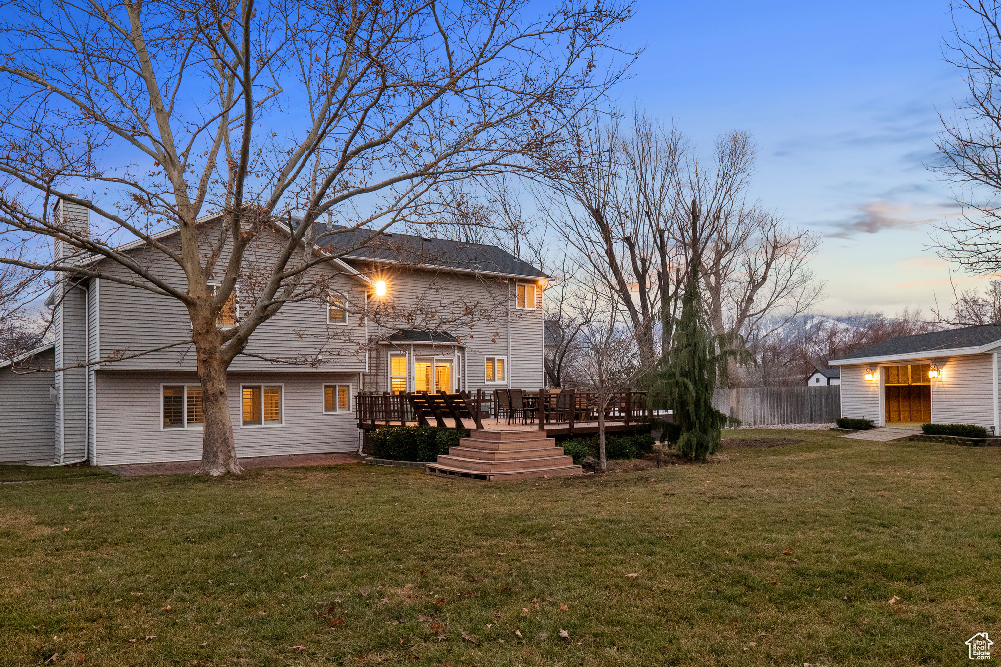 Back house at dusk with a yard and a wooden deck