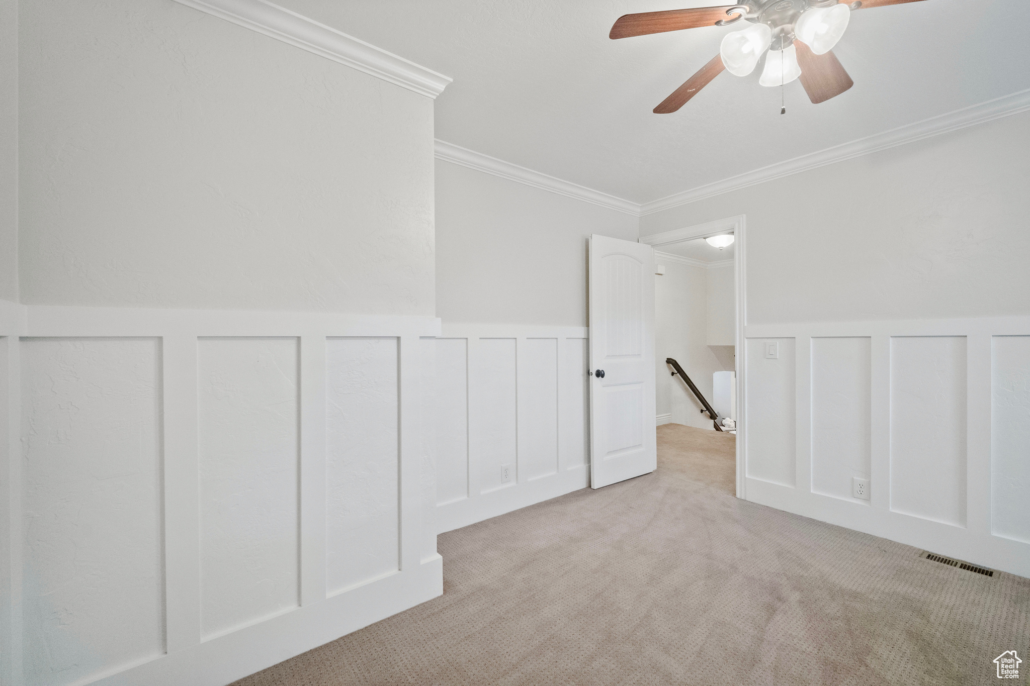 Carpeted spare room featuring ceiling fan and crown molding