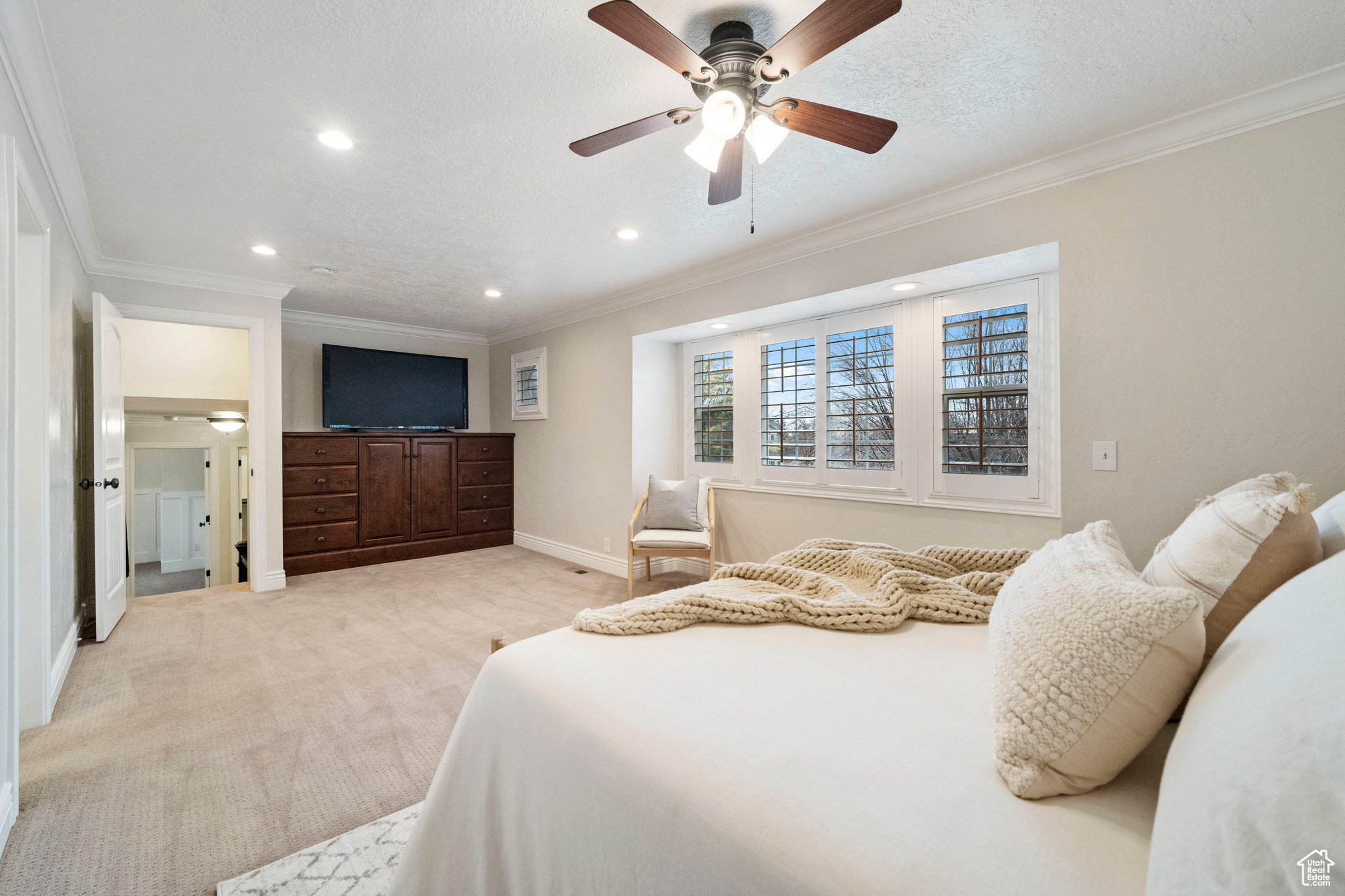 Carpeted bedroom with ceiling fan and ornamental molding