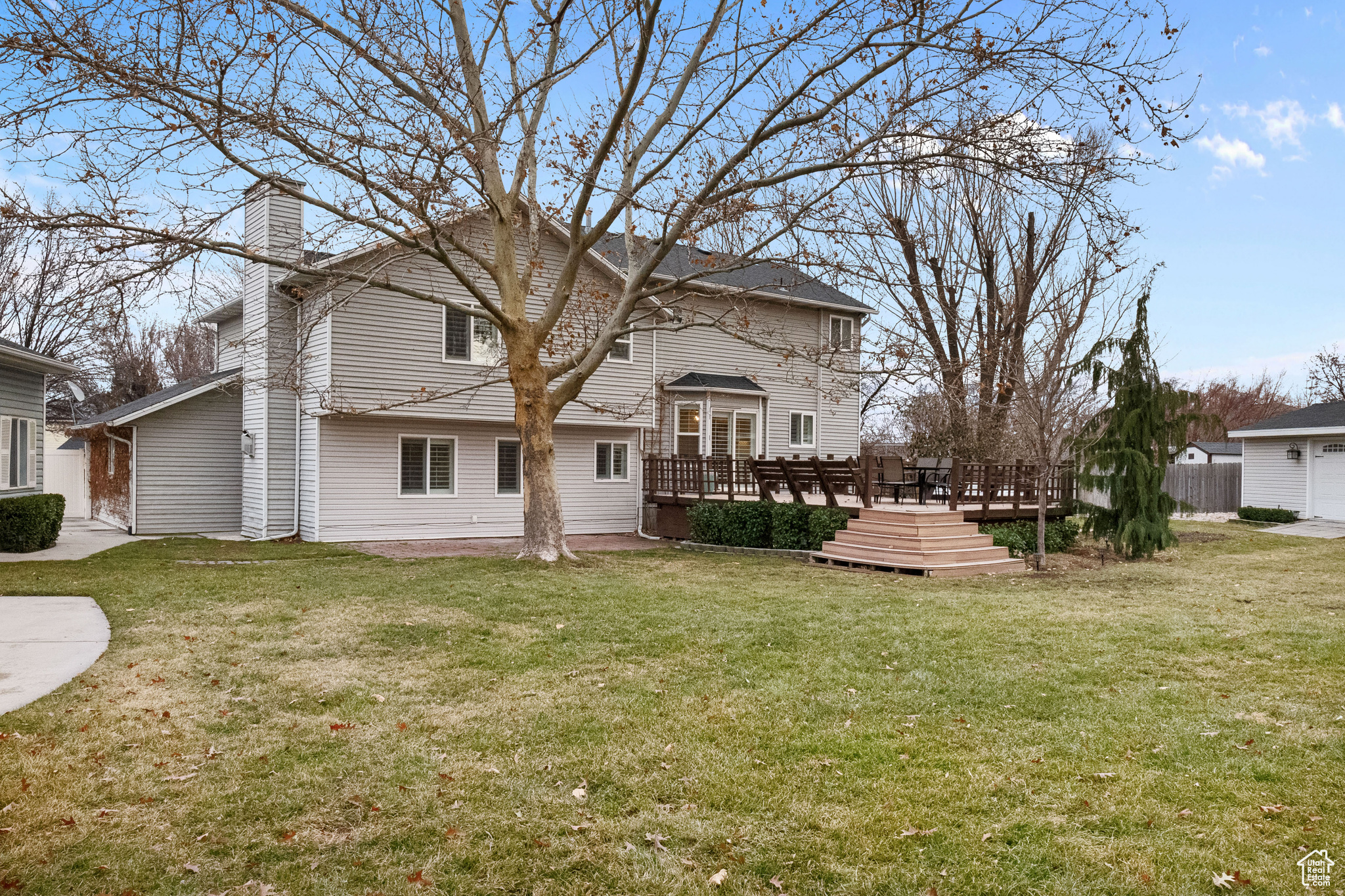 Back of house featuring a lawn and a wooden deck