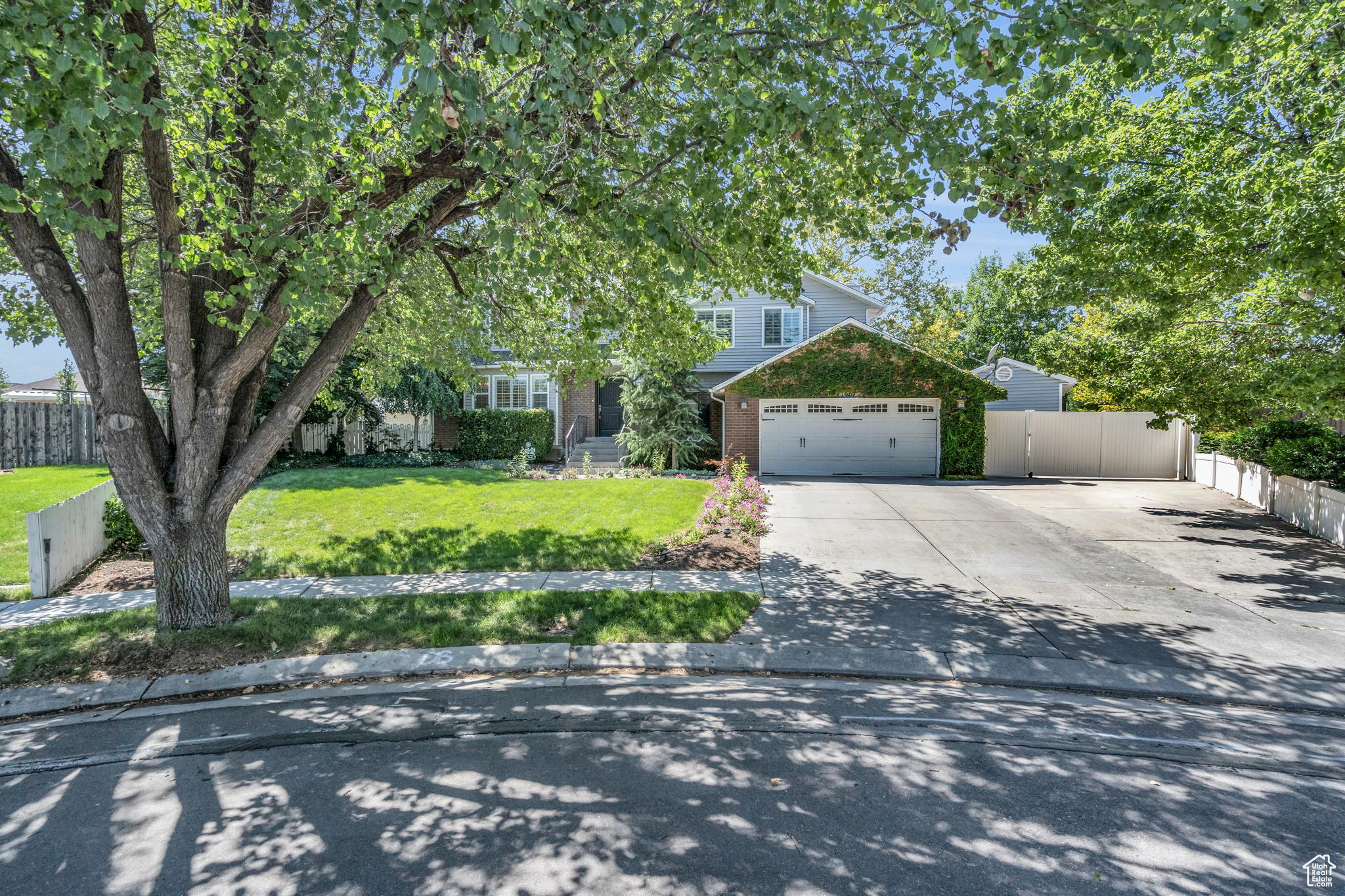 View of property hidden behind natural elements featuring a front yard and a garage