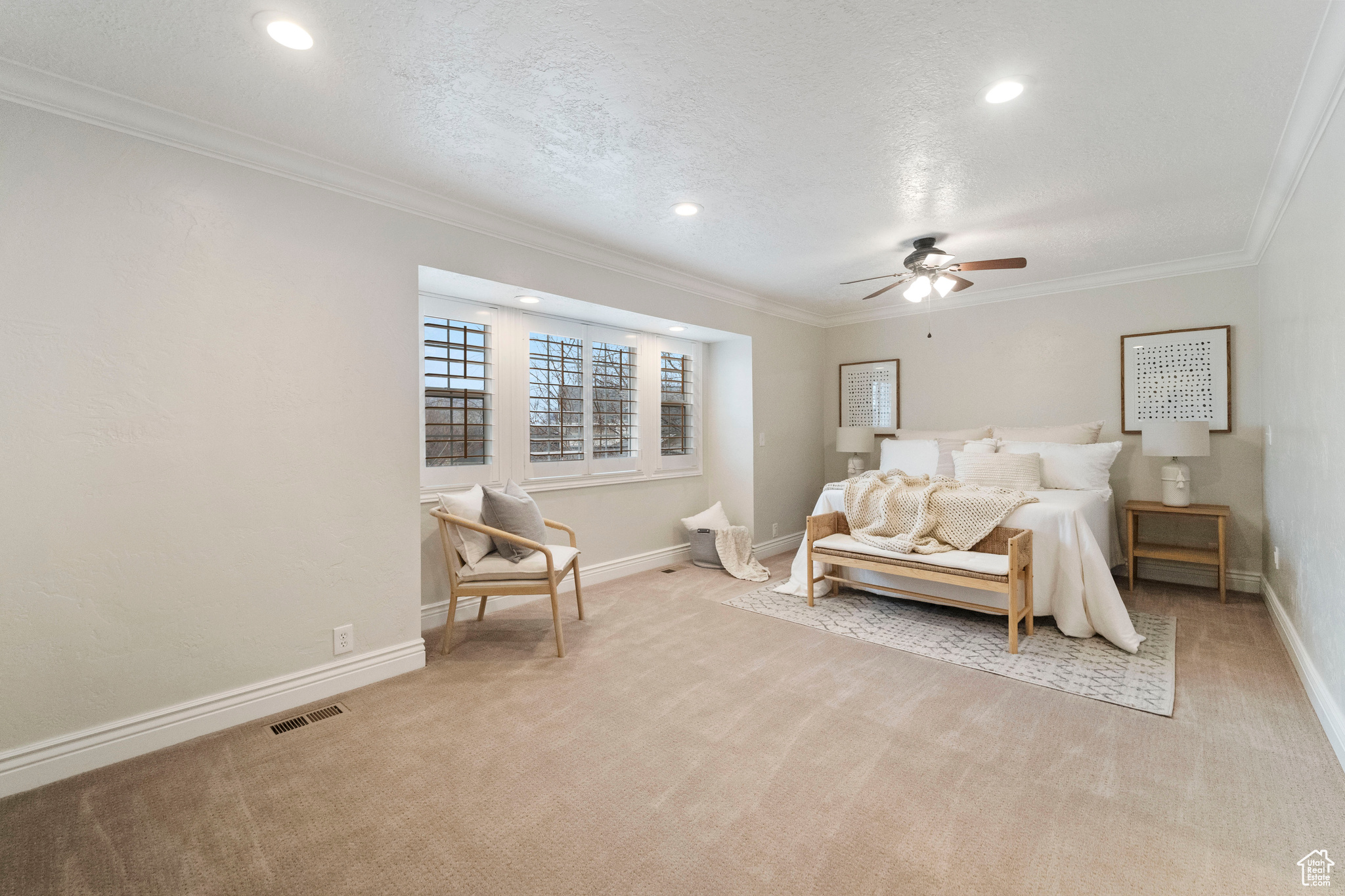 Bedroom with a textured ceiling, light colored carpet, ceiling fan, and ornamental molding