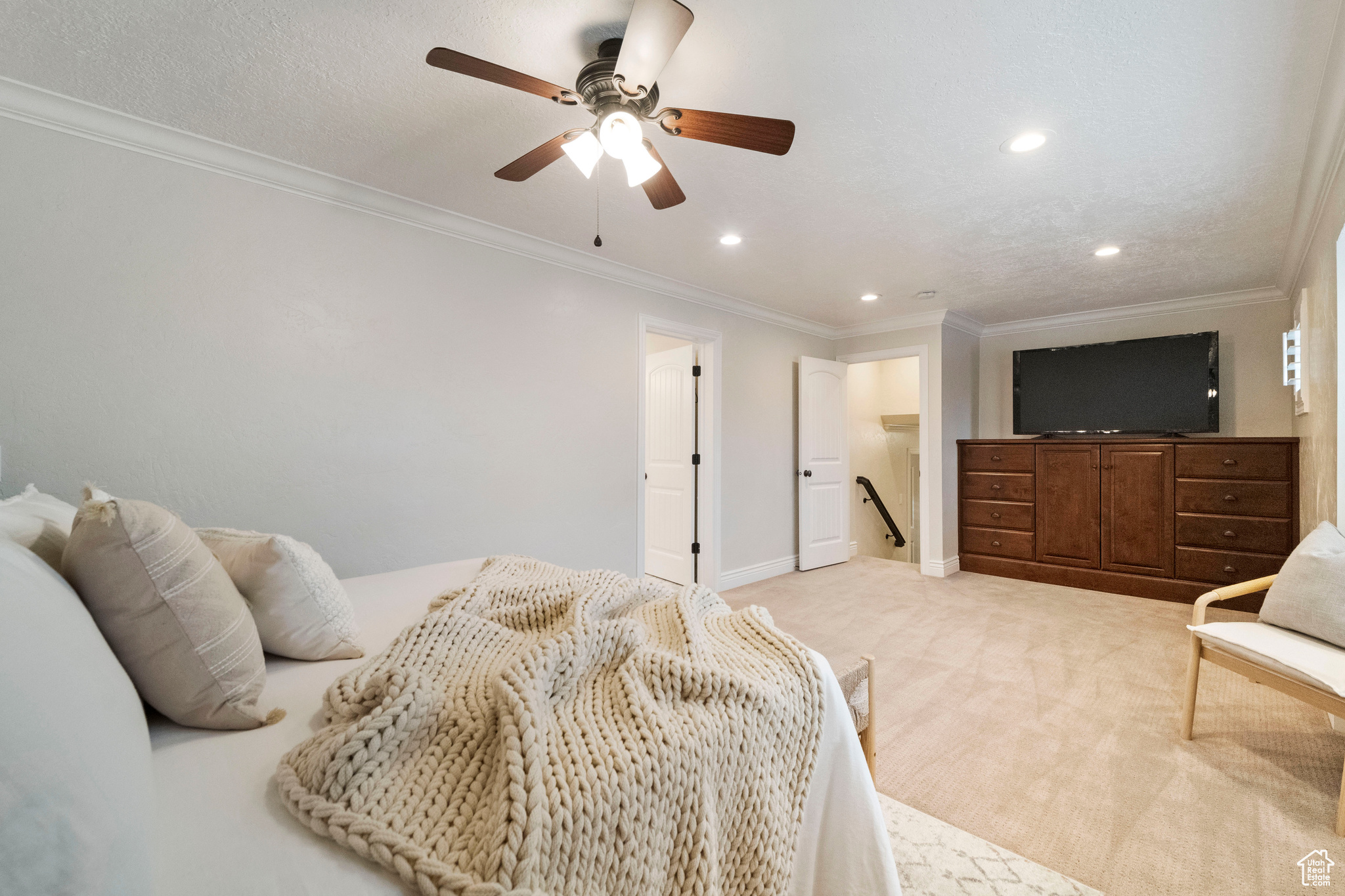 Bedroom with ceiling fan, crown molding, and light colored carpet