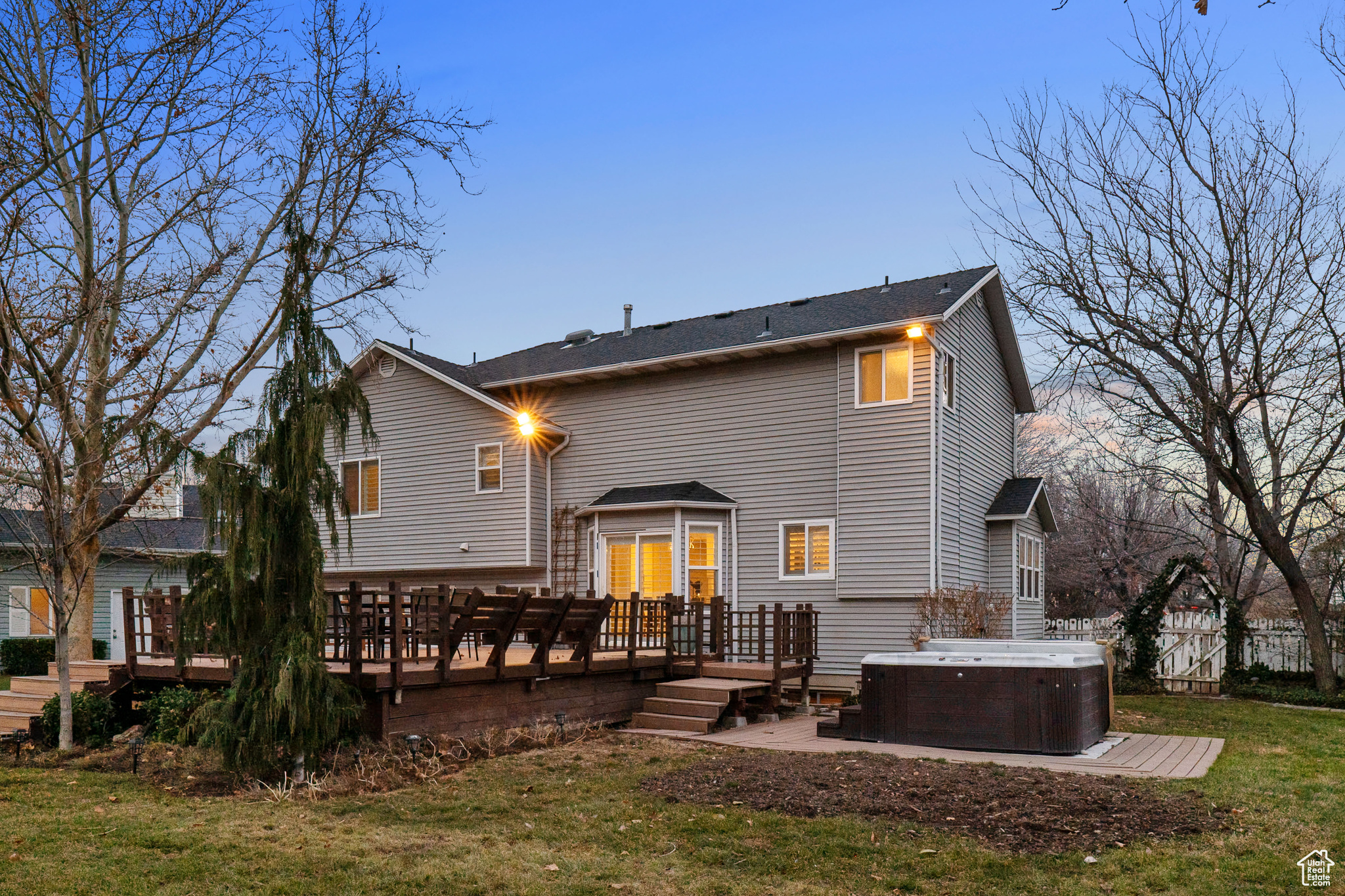 Rear view of house with a lawn, a wooden deck, and a hot tub