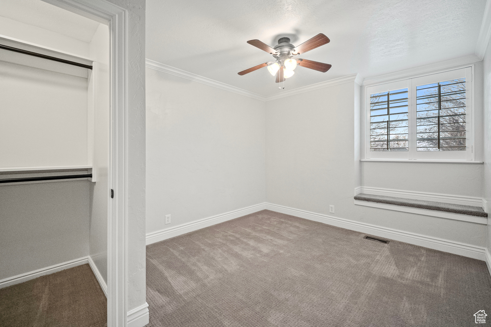 Unfurnished bedroom featuring ceiling fan, a closet, carpet, and ornamental molding