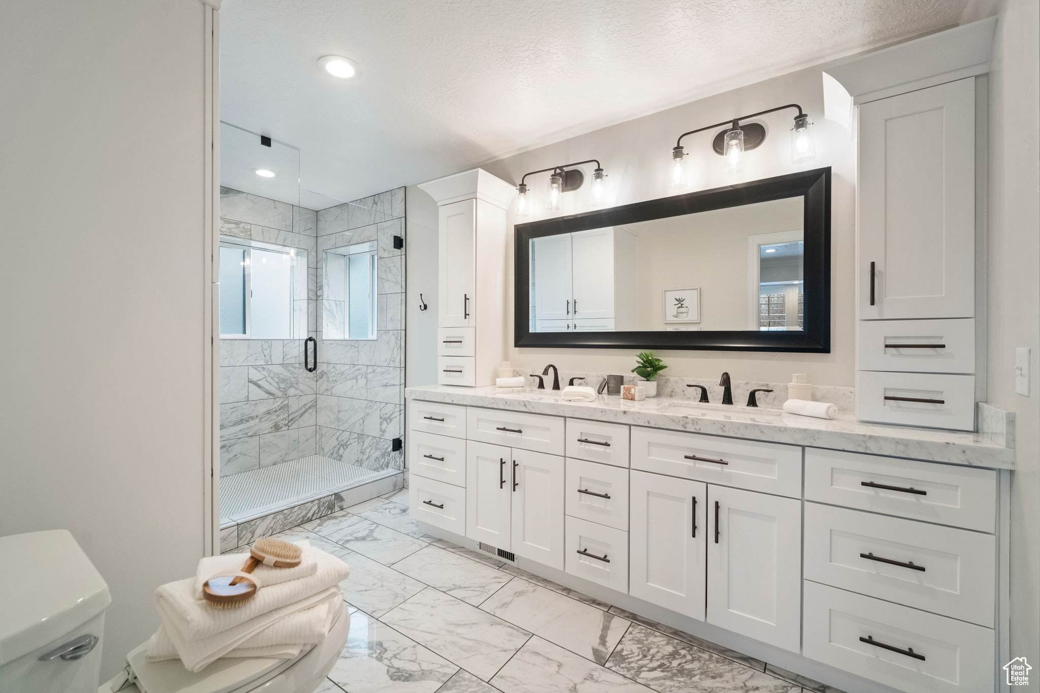 Bathroom featuring a textured ceiling, vanity, toilet, and a shower with door