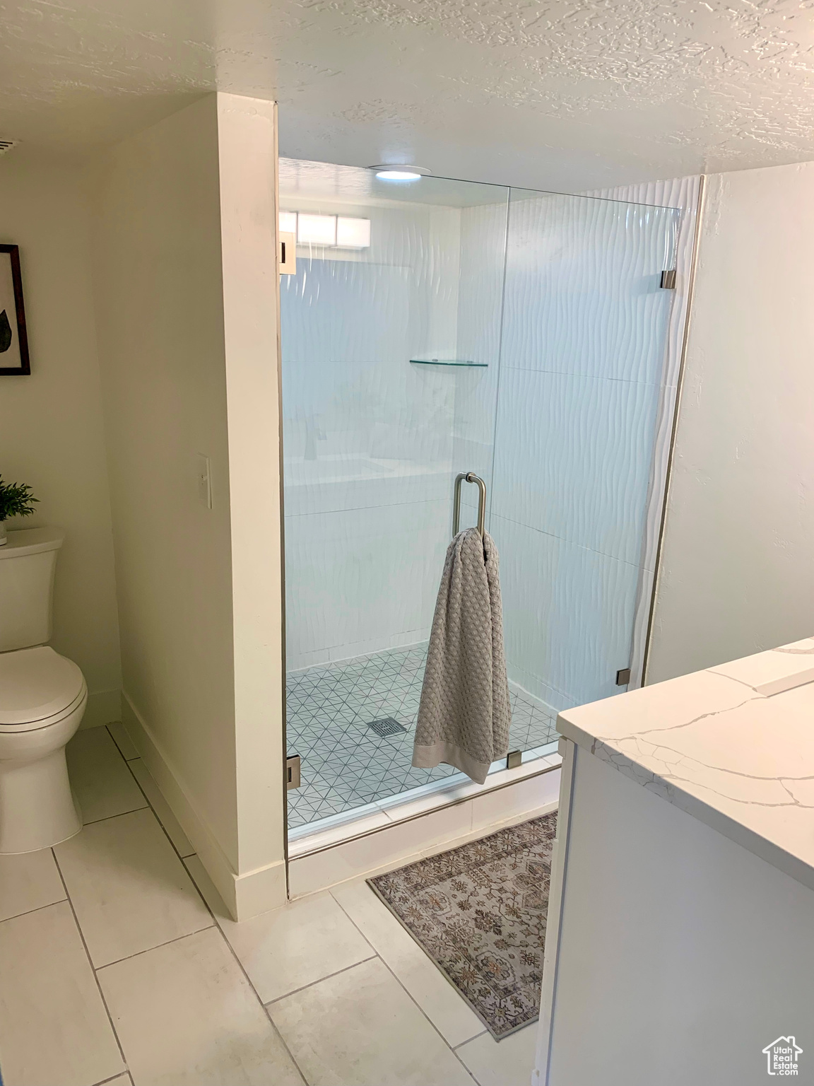 Bathroom with tile patterned floors, a textured ceiling, and an enclosed shower