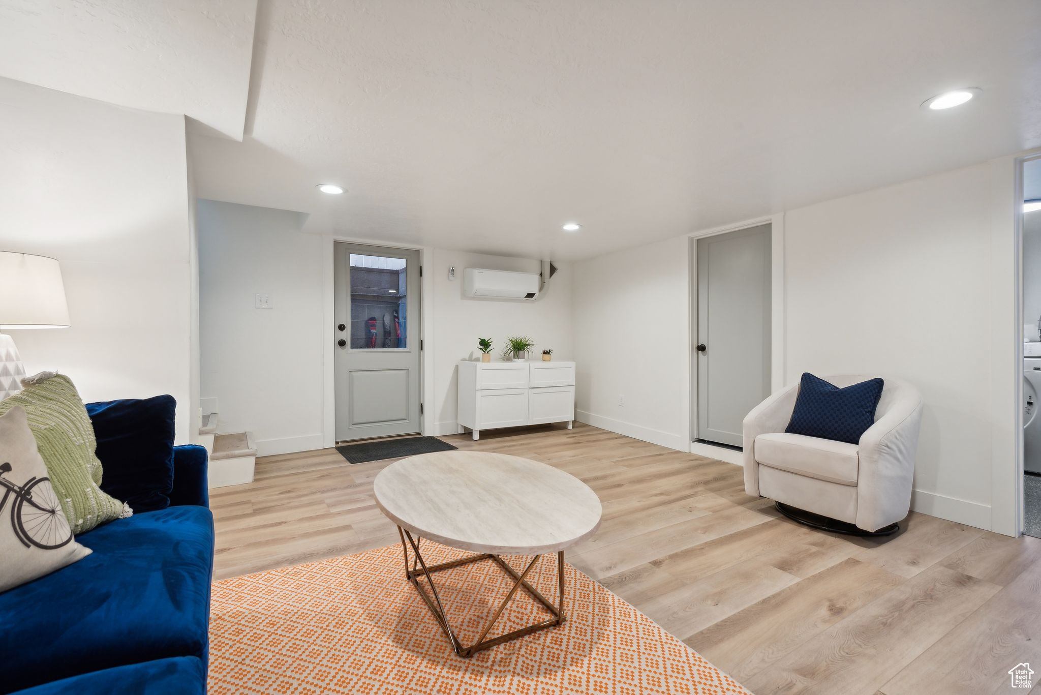 Living room with a wall mounted air conditioner and light wood-type flooring