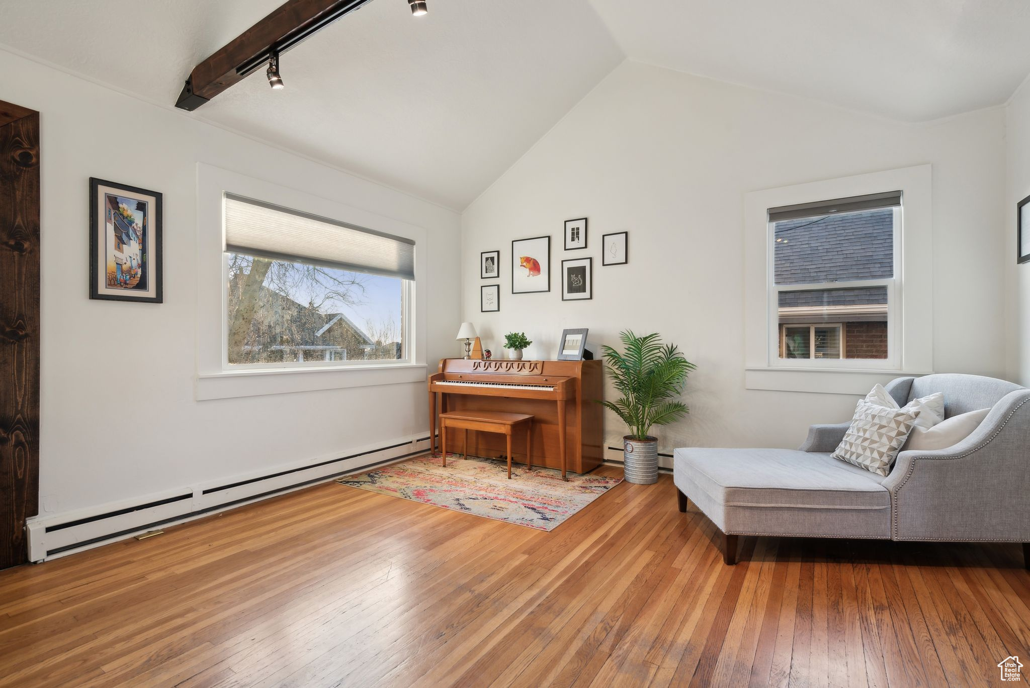 Sitting room featuring a baseboard radiator, track lighting, hardwood / wood-style flooring, and lofted ceiling