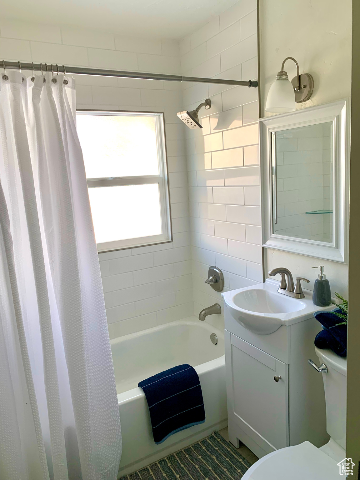 Full bathroom with vanity, shower / bathtub combination with curtain, and toilet