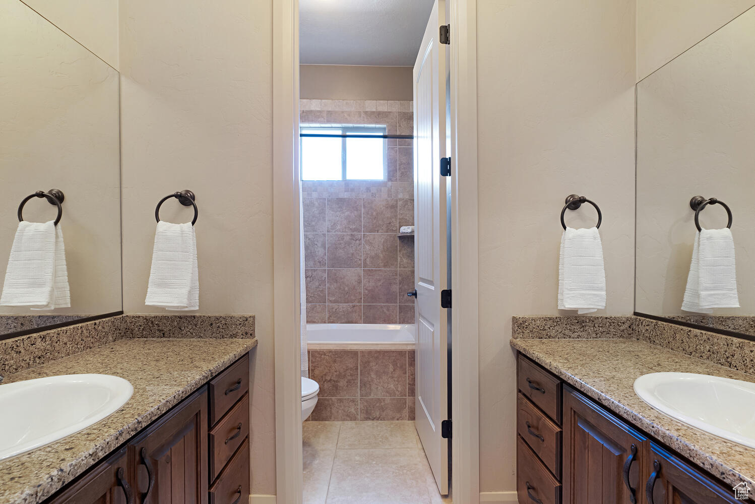 Bathroom featuring toilet, vanity, a relaxing tiled tub, and tile patterned floors