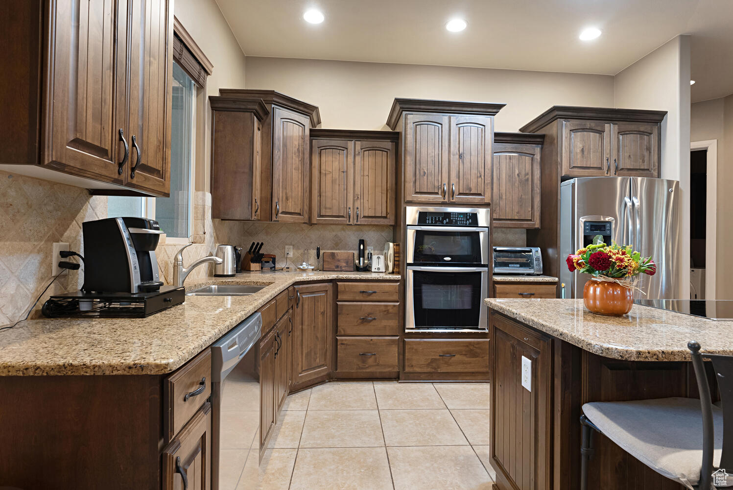 Kitchen with appliances with stainless steel finishes, tasteful backsplash, dark brown cabinets, and sink