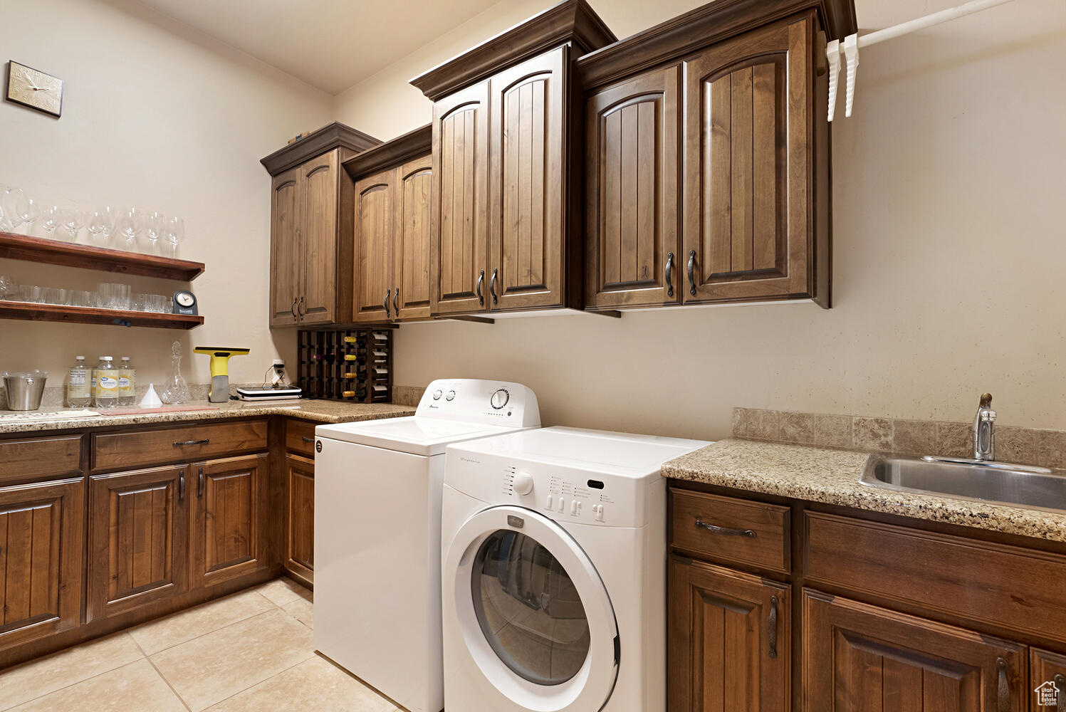 Clothes washing area featuring cabinets, separate washer and dryer, light tile patterned floors, and wet bar