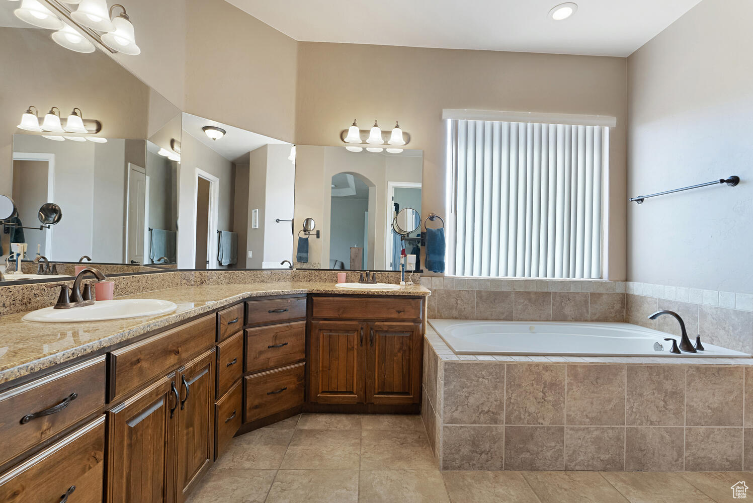 Bathroom featuring tile patterned flooring, vanity, and tiled bath