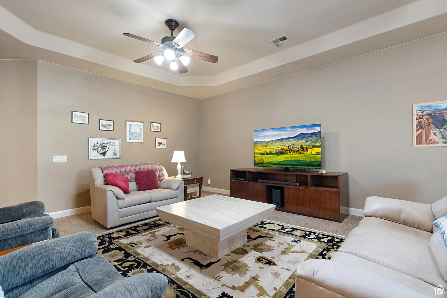 Carpeted living room with a tray ceiling and ceiling fan