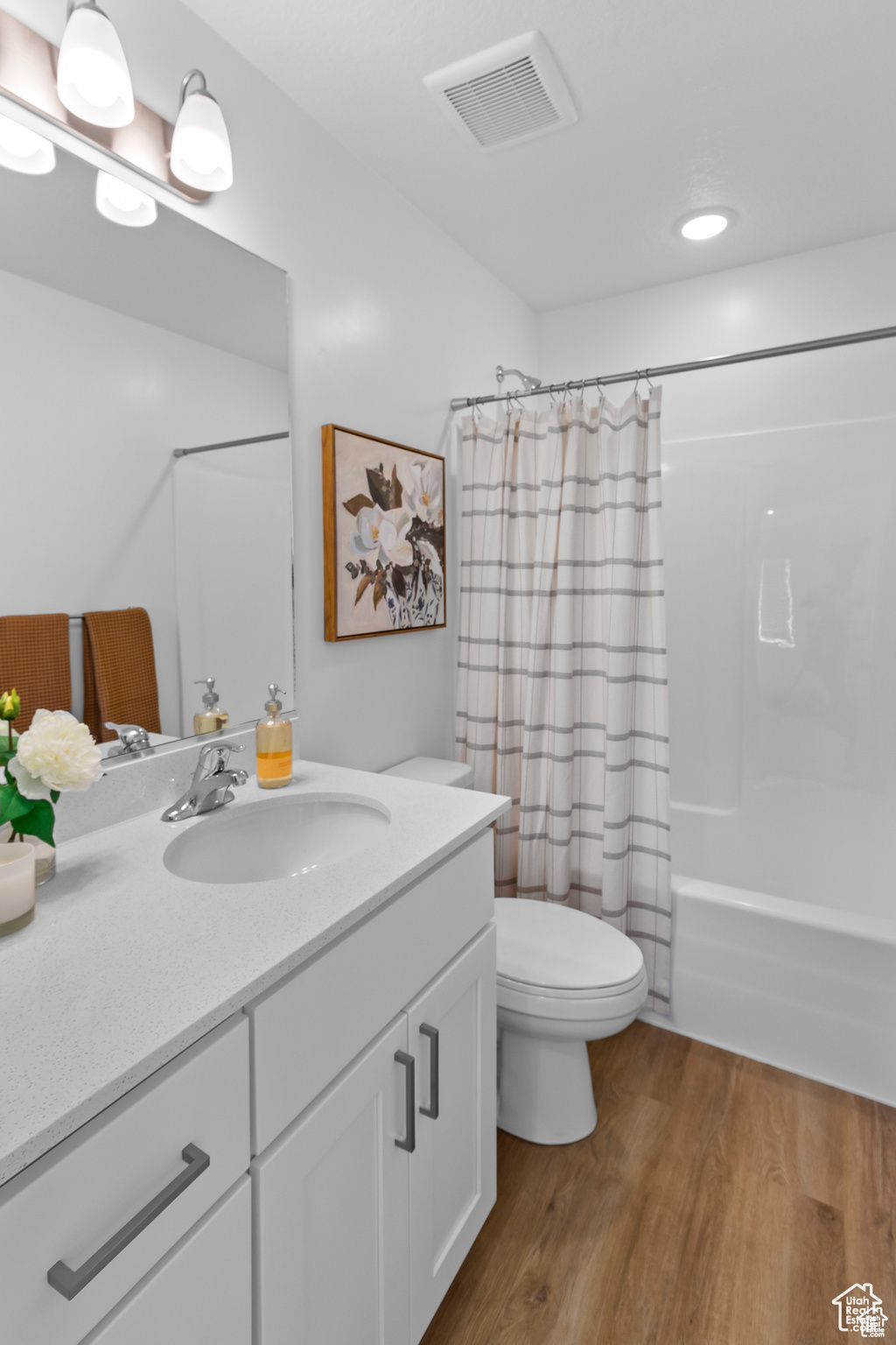 Full bathroom with shower / bath combo, vanity, hardwood / wood-style flooring, and toilet