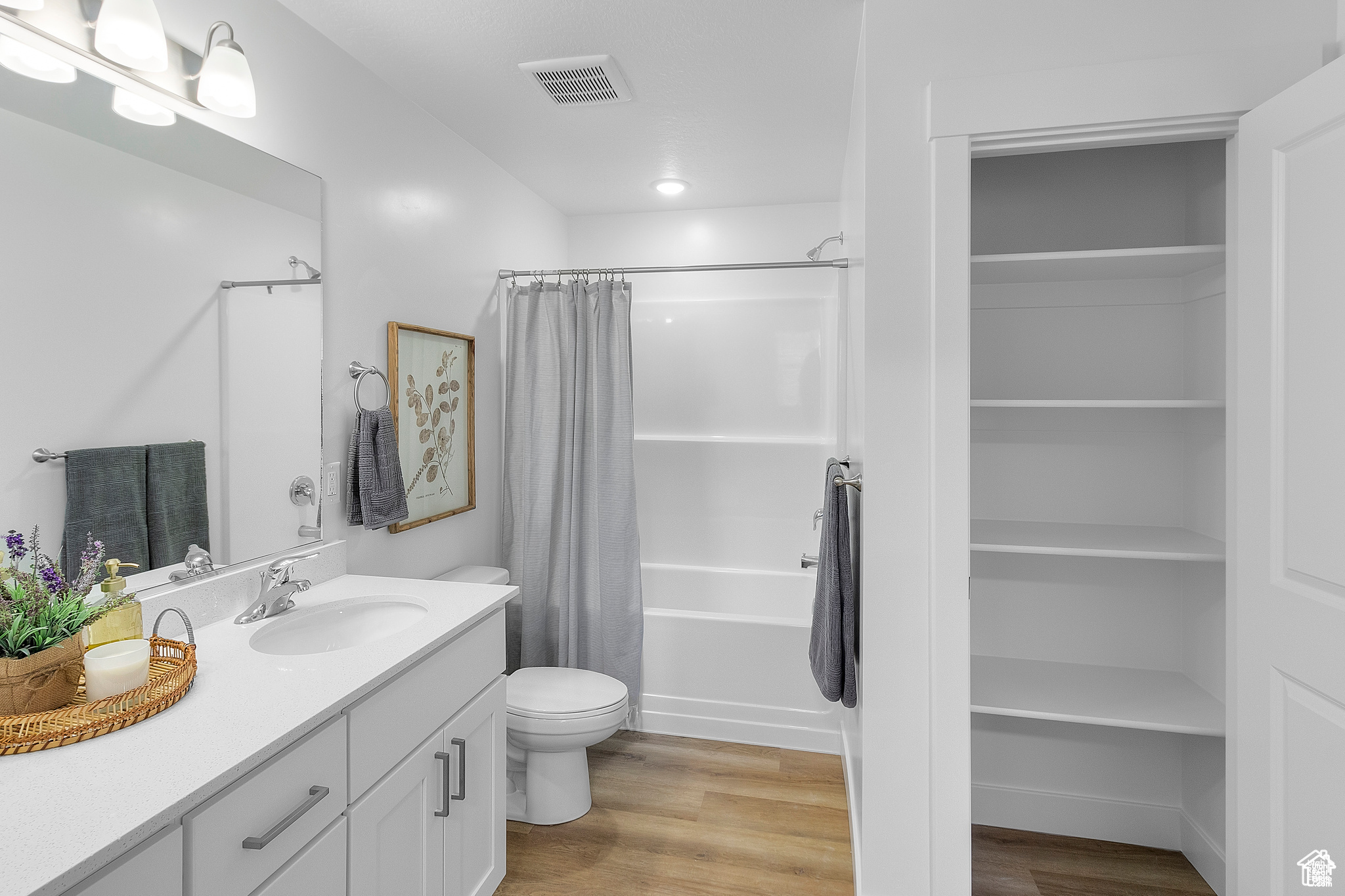 Full bathroom featuring hardwood / wood-style floors, vanity, toilet, and shower / bath combination with curtain