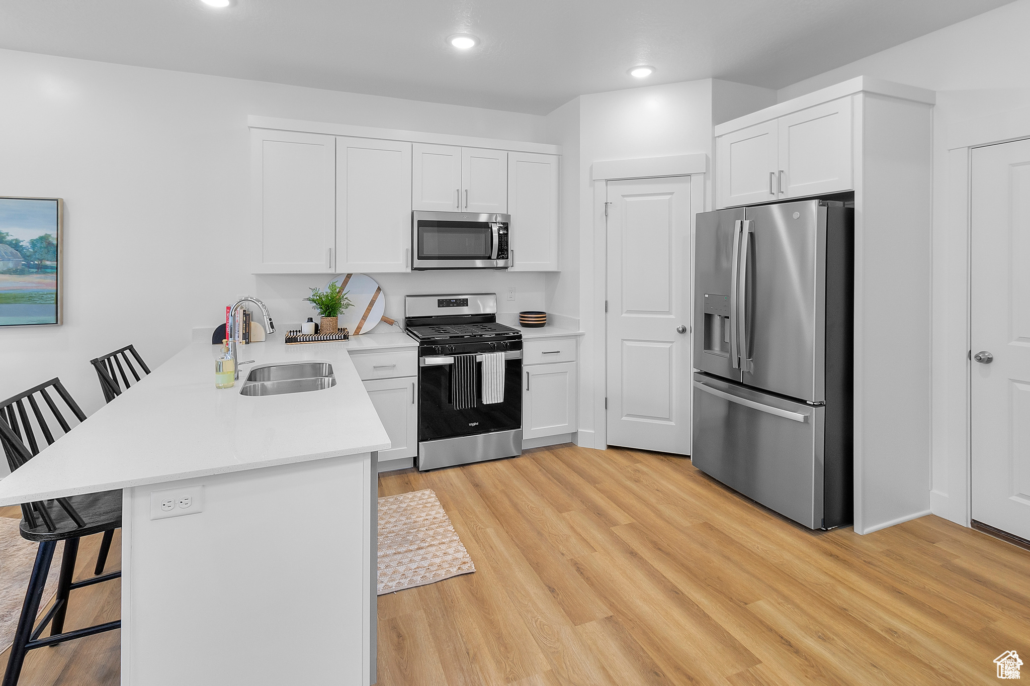 Kitchen with white cabinetry, sink, a kitchen breakfast bar, kitchen peninsula, and appliances with stainless steel finishes