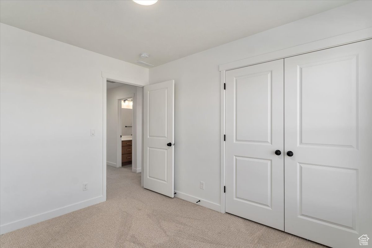 Unfurnished bedroom featuring light carpet and a closet