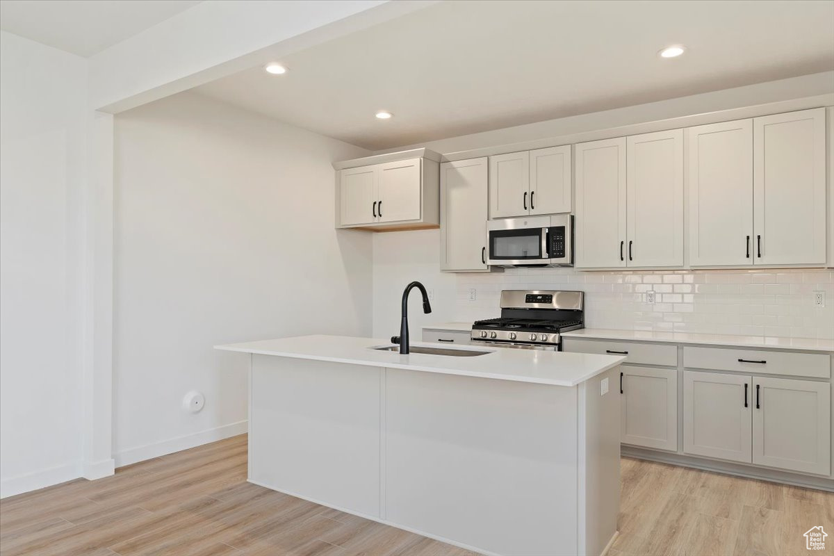 Kitchen featuring a center island with sink, light hardwood / wood-style flooring, stainless steel appliances, and sink