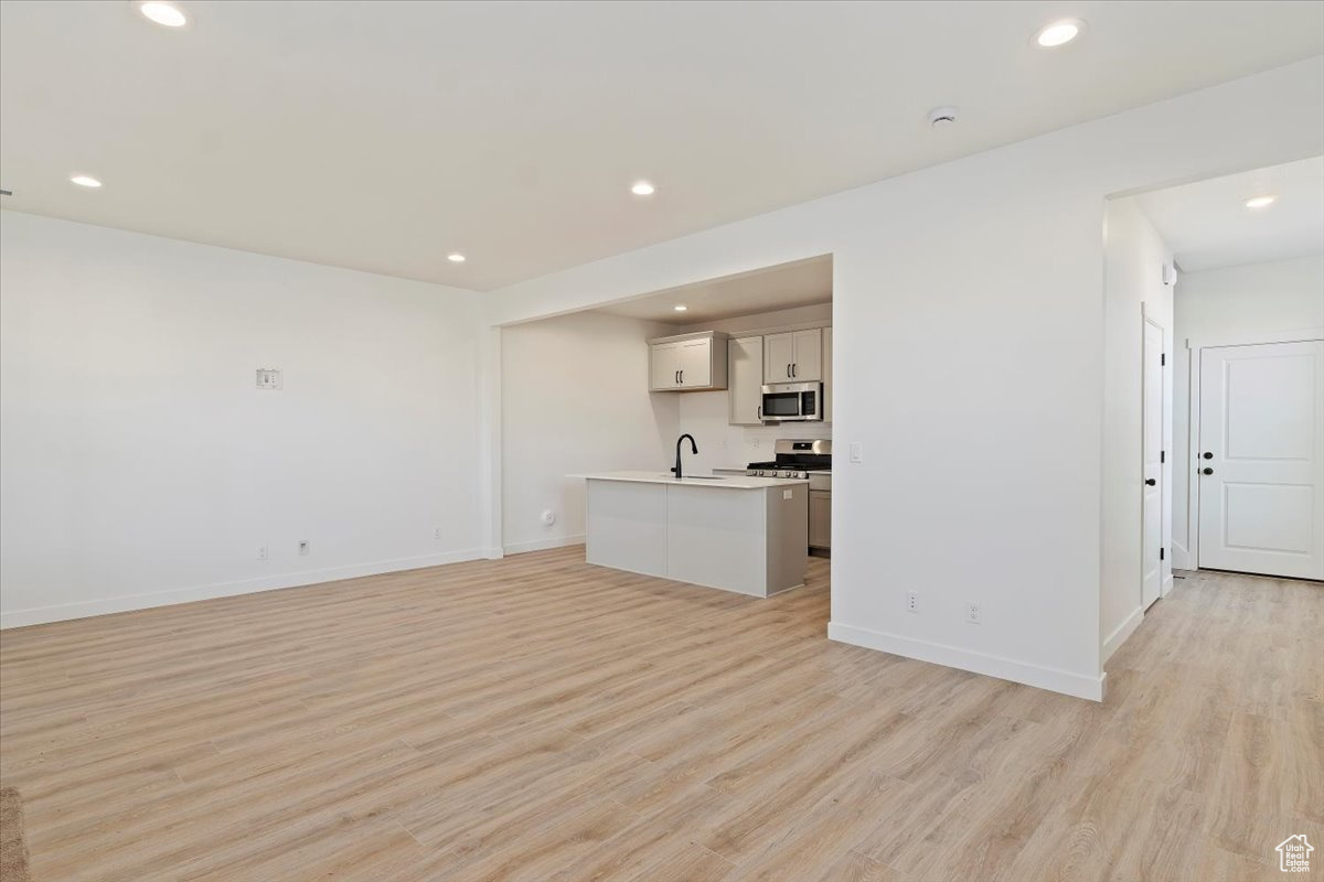 Unfurnished living room featuring sink and light wood-type flooring