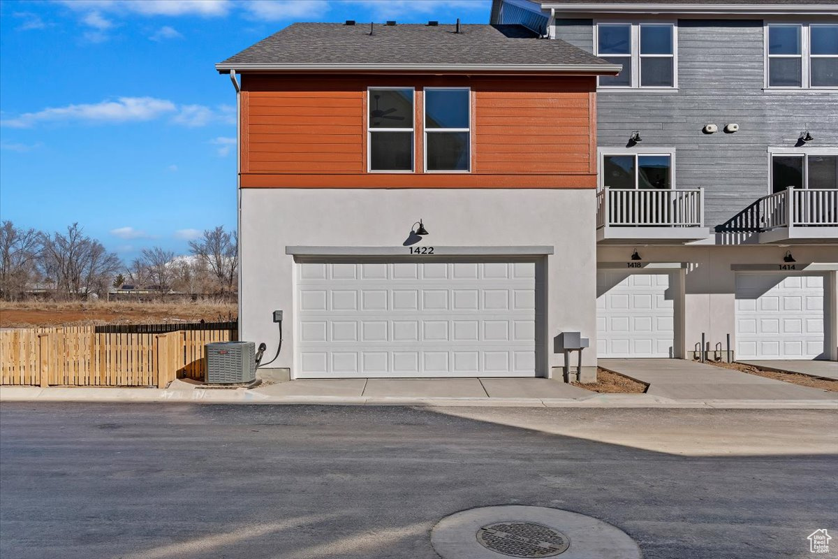 Rear view of property with a garage and central air condition unit