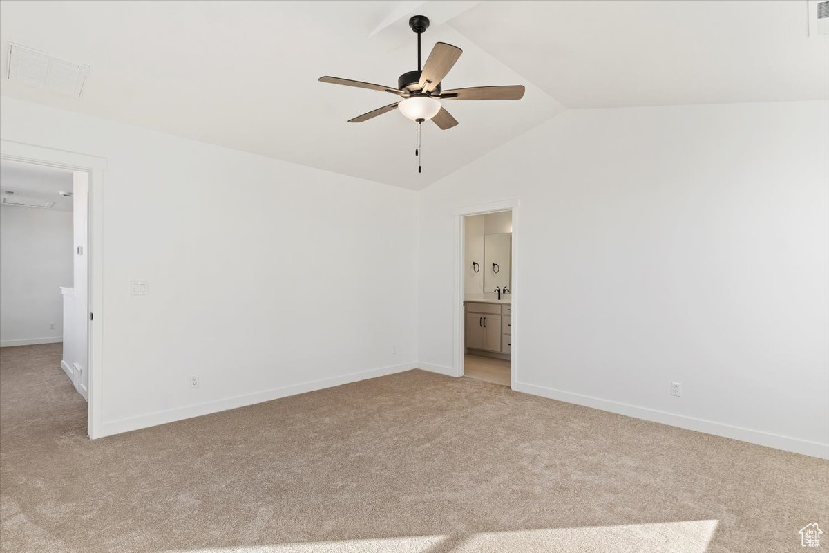 Unfurnished bedroom with ceiling fan, lofted ceiling, light carpet, and connected bathroom