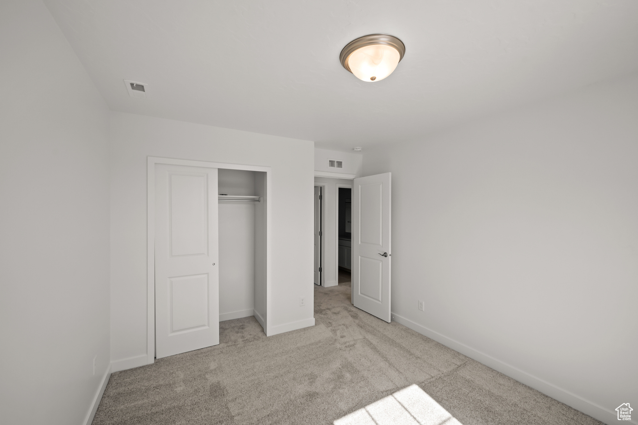 Unfurnished bedroom with light colored carpet and a closet