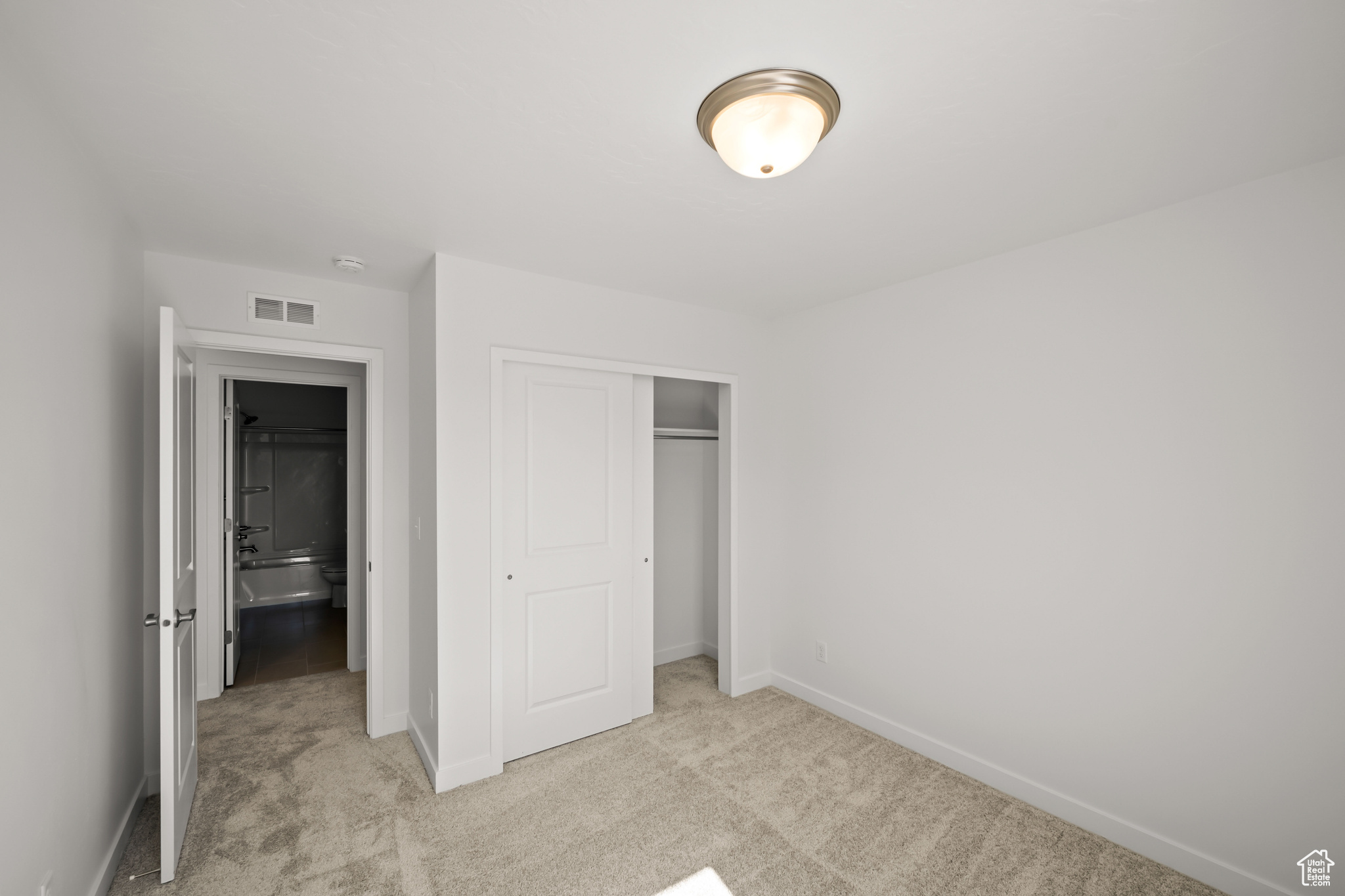 Unfurnished bedroom featuring a closet and light colored carpet