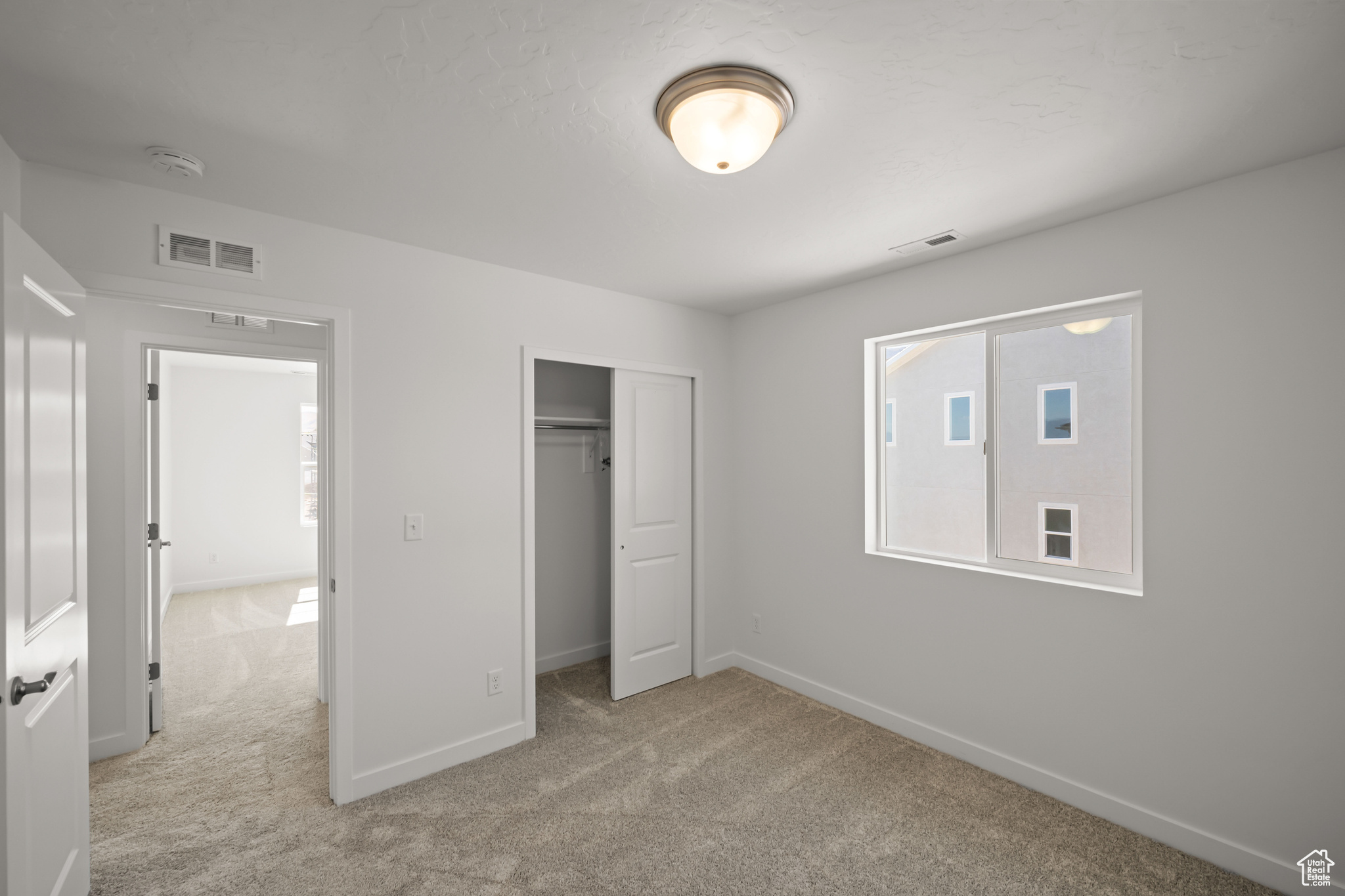 Unfurnished bedroom featuring light carpet and a closet