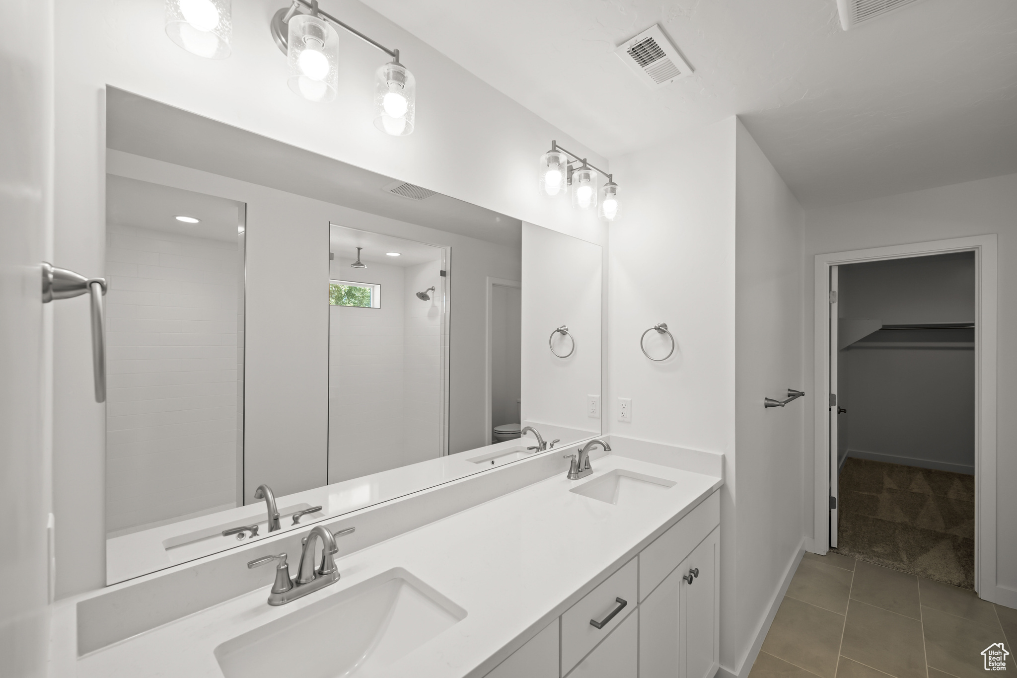 Bathroom featuring tile patterned flooring, vanity, and walk in shower