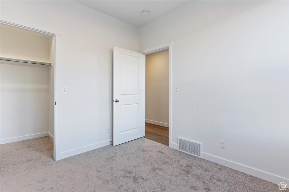 Unfurnished bedroom featuring light carpet and a closet