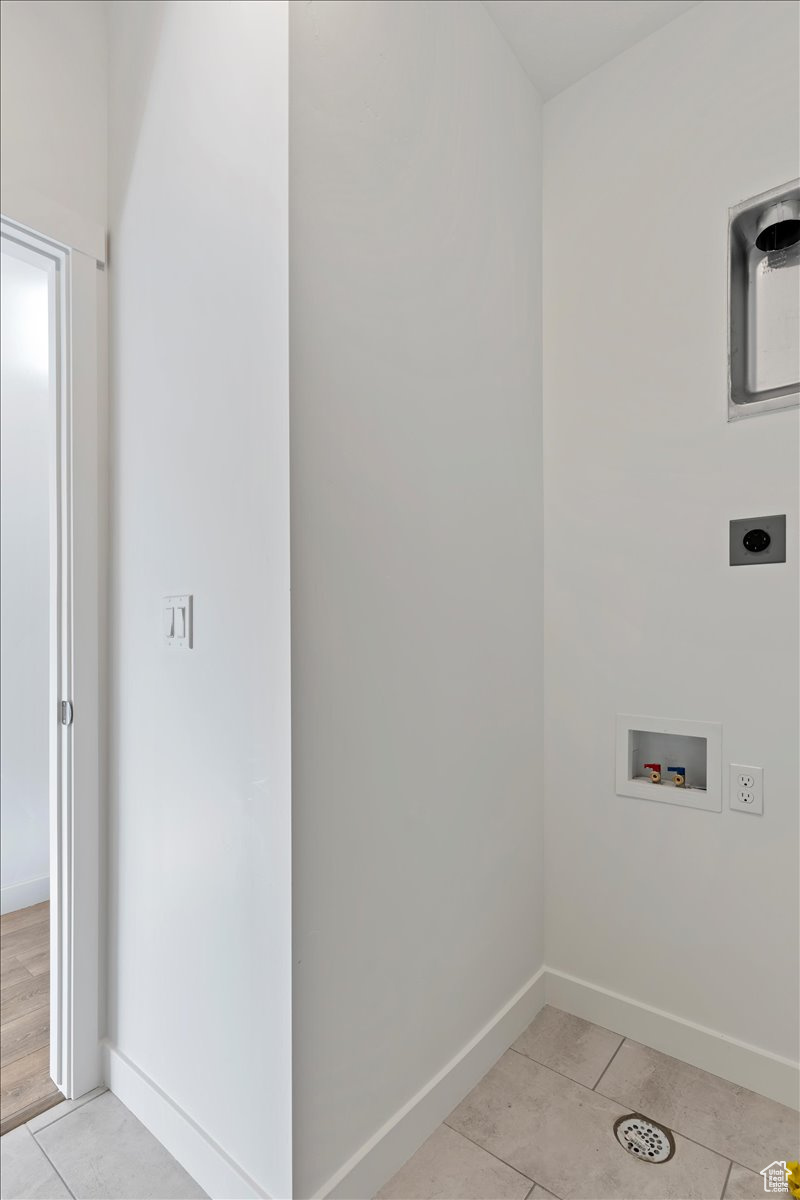 Washroom with hookup for a washing machine, light tile patterned floors, and electric dryer hookup