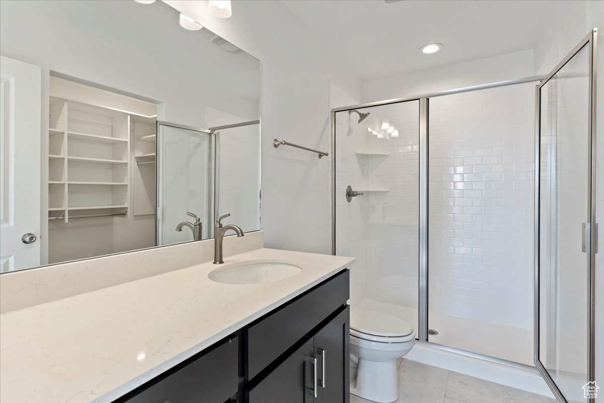 Bathroom featuring toilet, tile patterned flooring, vanity, and walk in shower