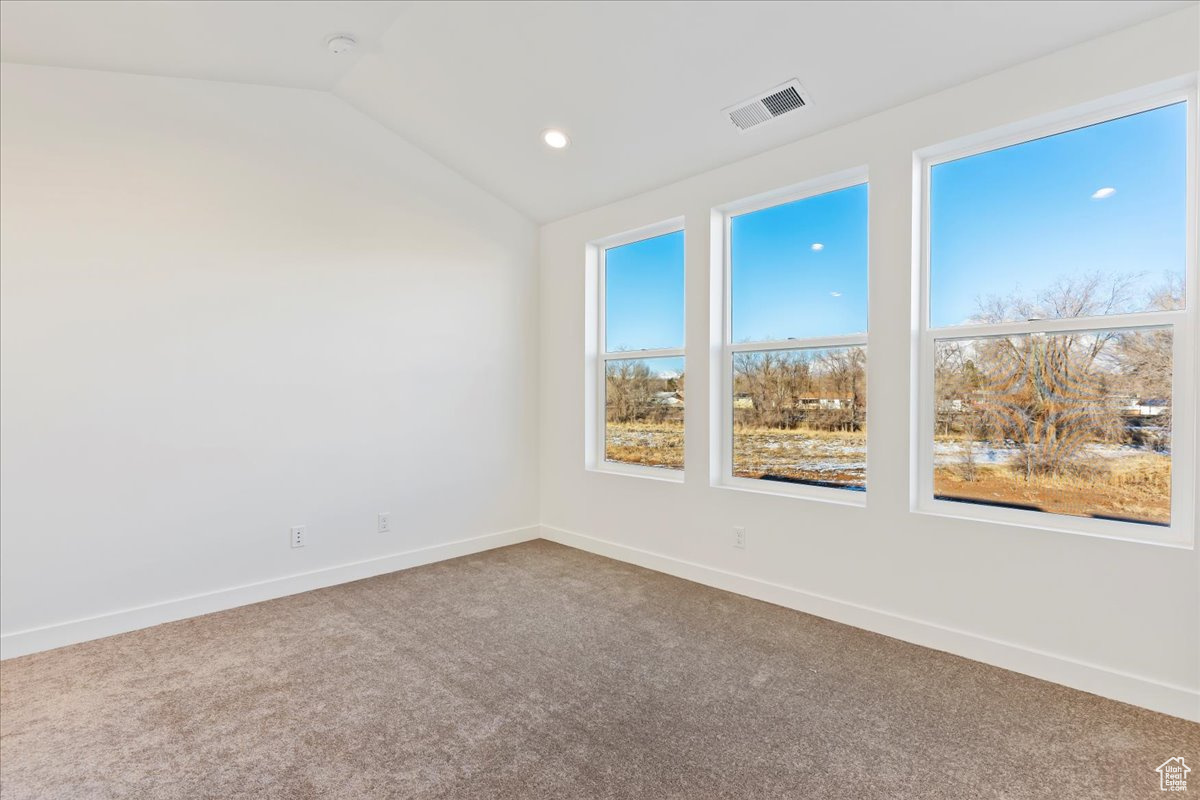 Carpeted spare room with vaulted ceiling