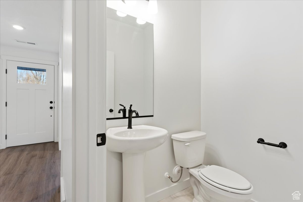 Bathroom with hardwood / wood-style flooring, toilet, and sink