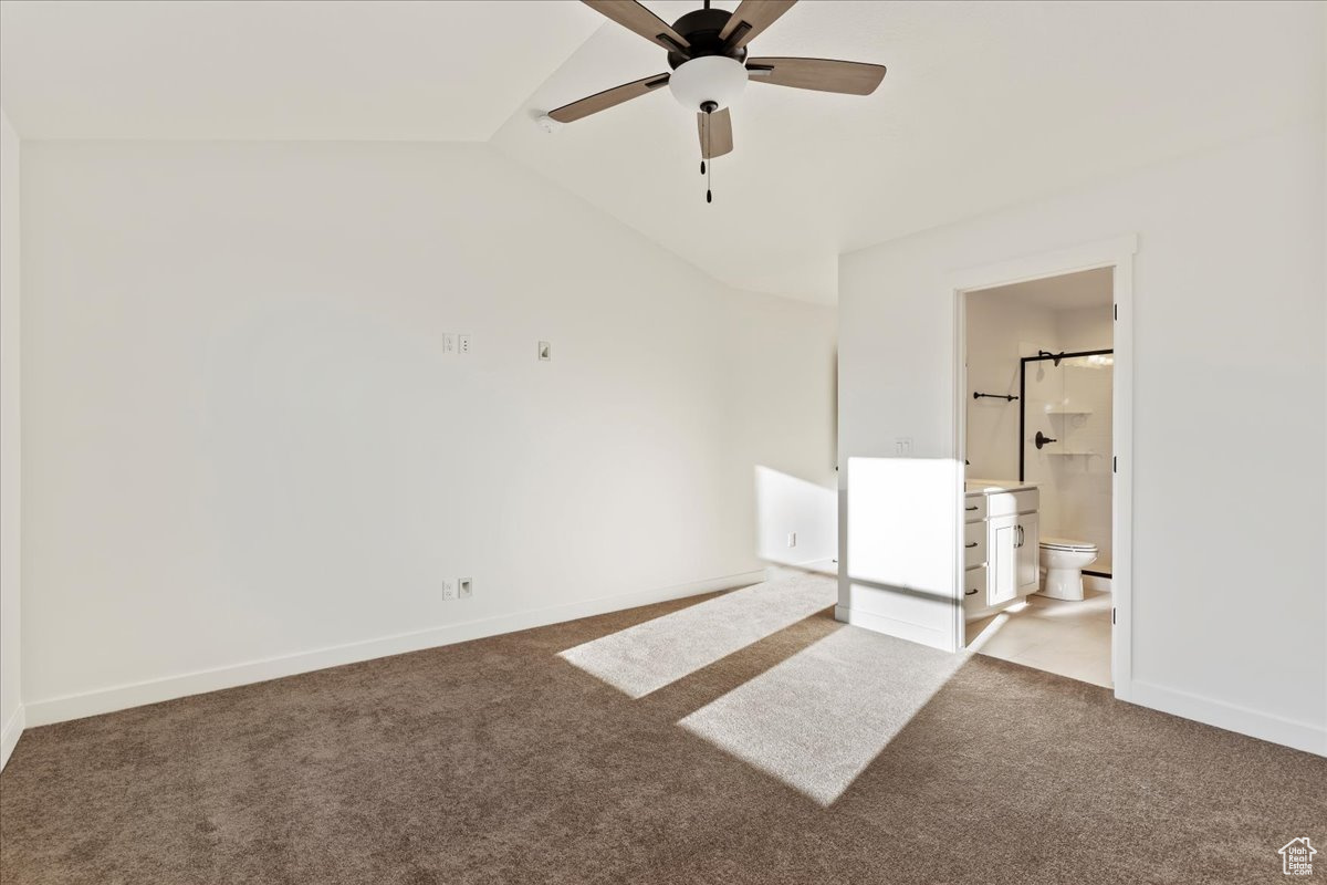 Carpeted empty room with ceiling fan and vaulted ceiling