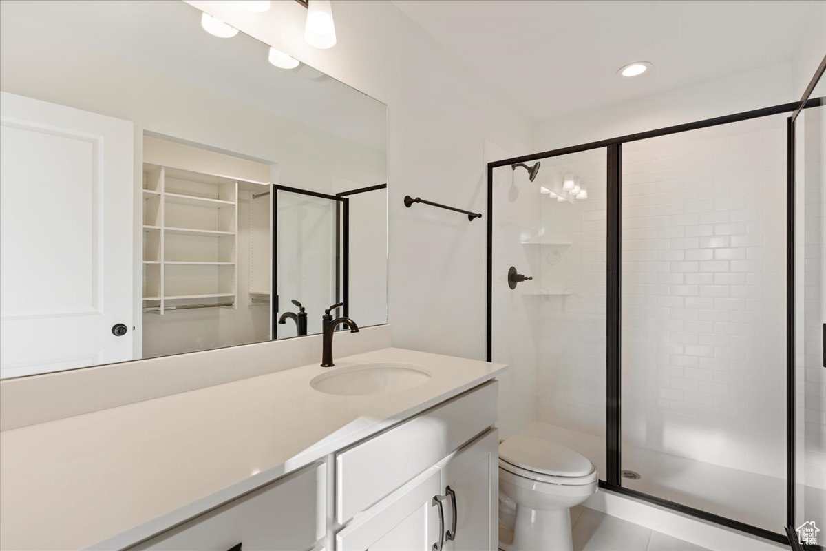 Bathroom with tile patterned floors, vanity, toilet, and a shower with door