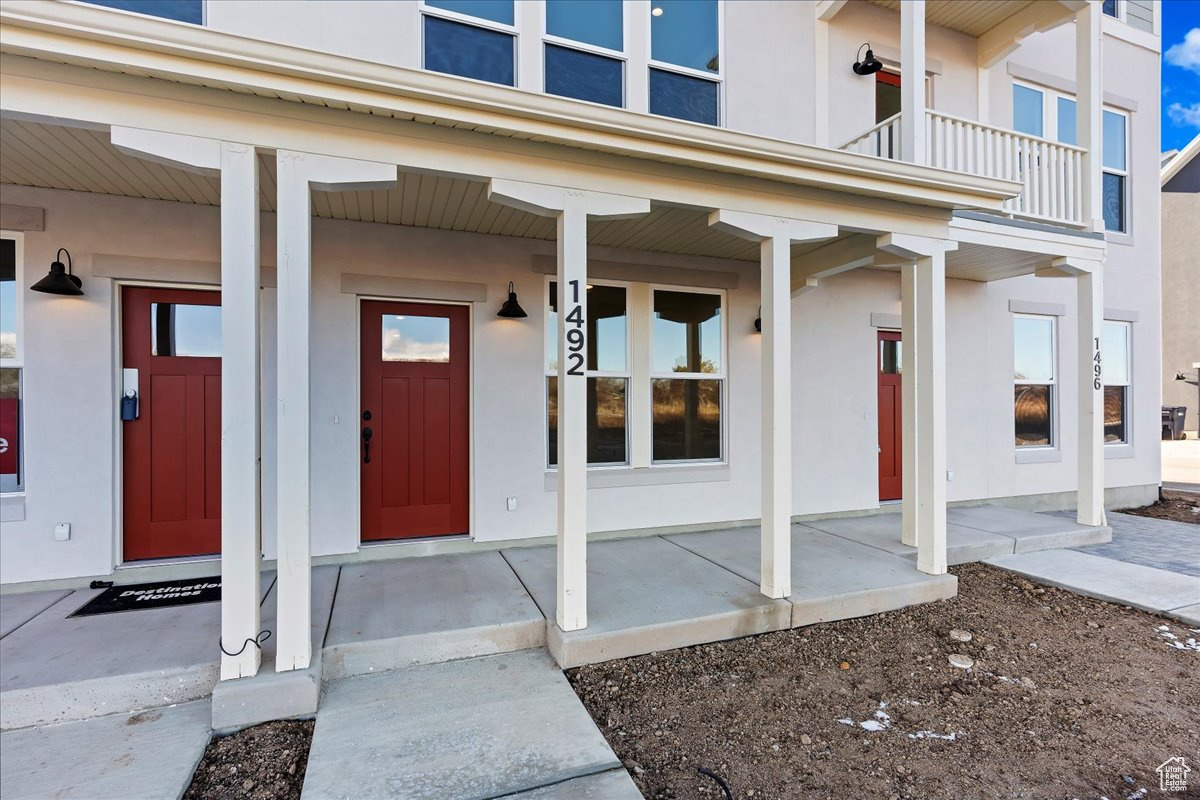 Entrance to property featuring a porch and a balcony