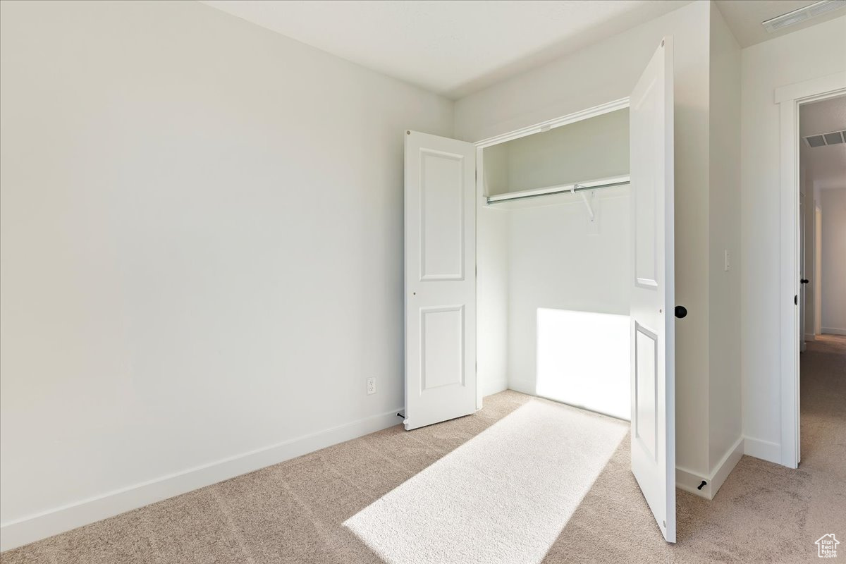 Bedroom featuring light carpet and a closet