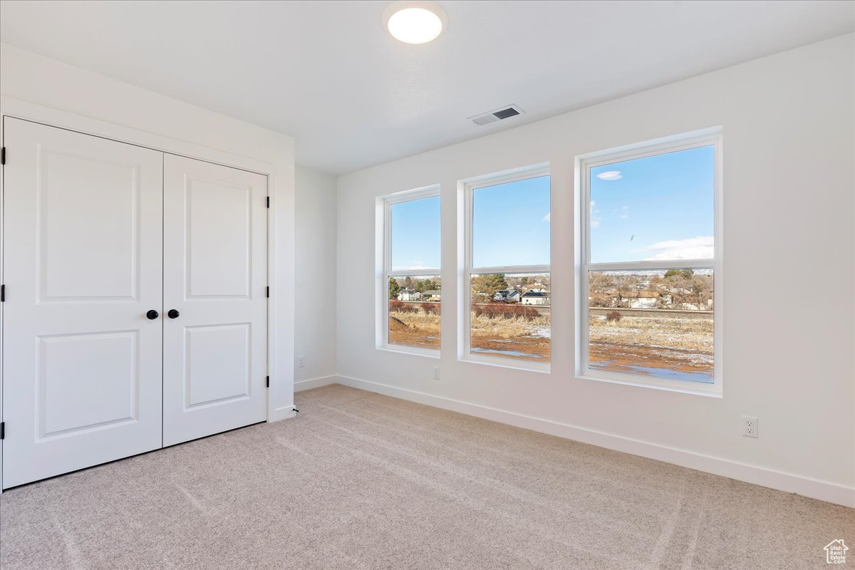 Unfurnished bedroom with light carpet and a closet