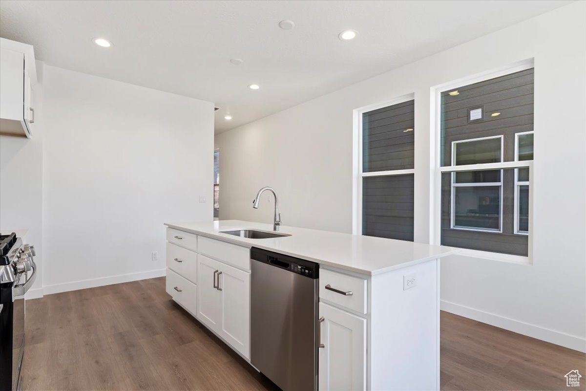 Kitchen featuring white cabinets, stainless steel appliances, a center island with sink, and sink