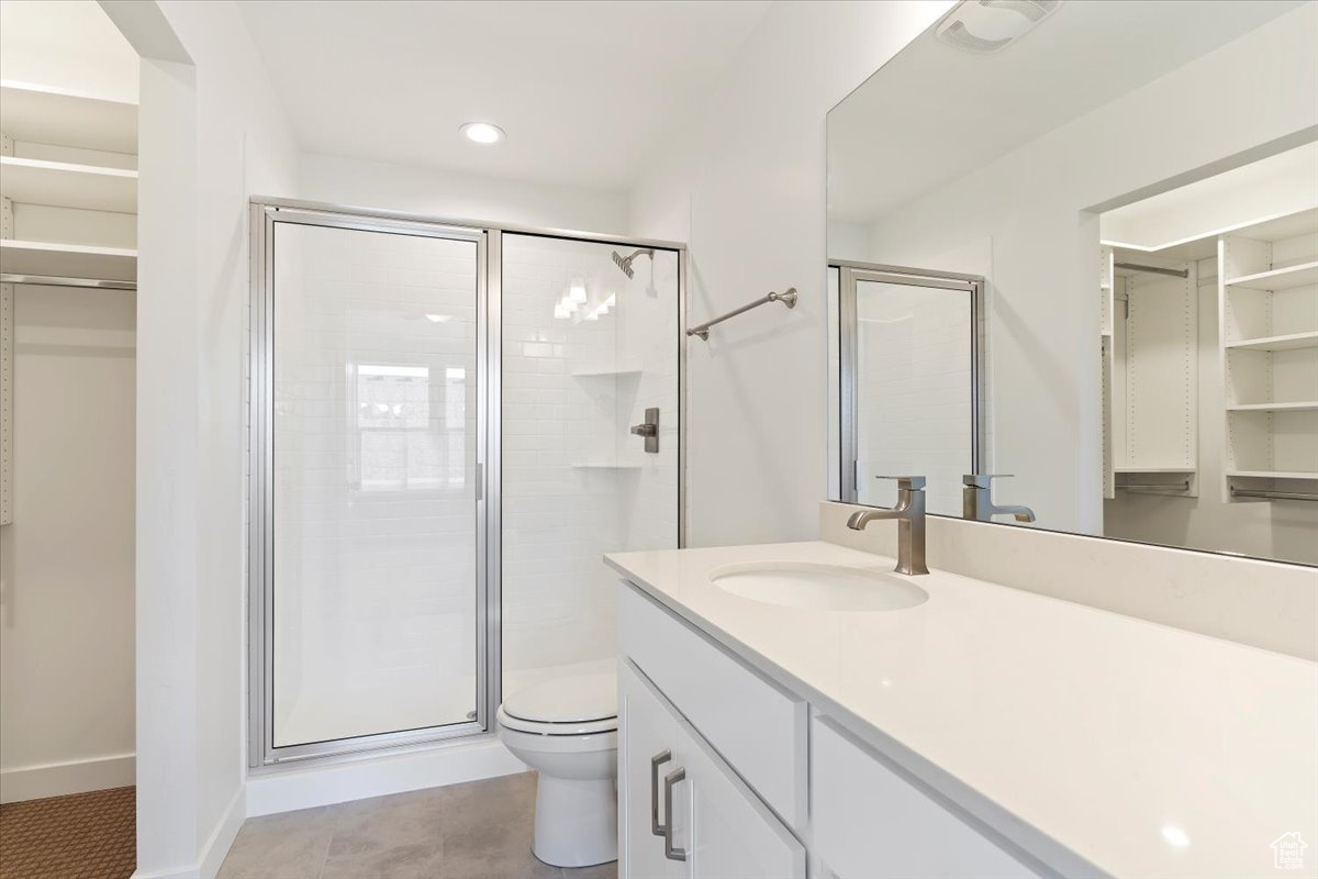 Bathroom featuring tile patterned floors, vanity, toilet, and walk in shower