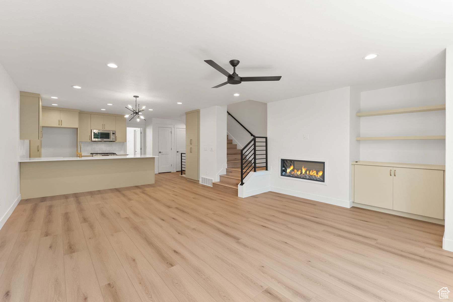 Family room with ceiling fan with notable chandelier and light wood-type flooring