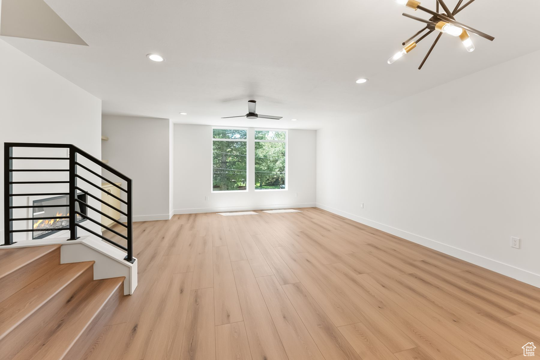 Family room featuring ceiling fan with notable chandelier and light hardwood / wood-style flooring