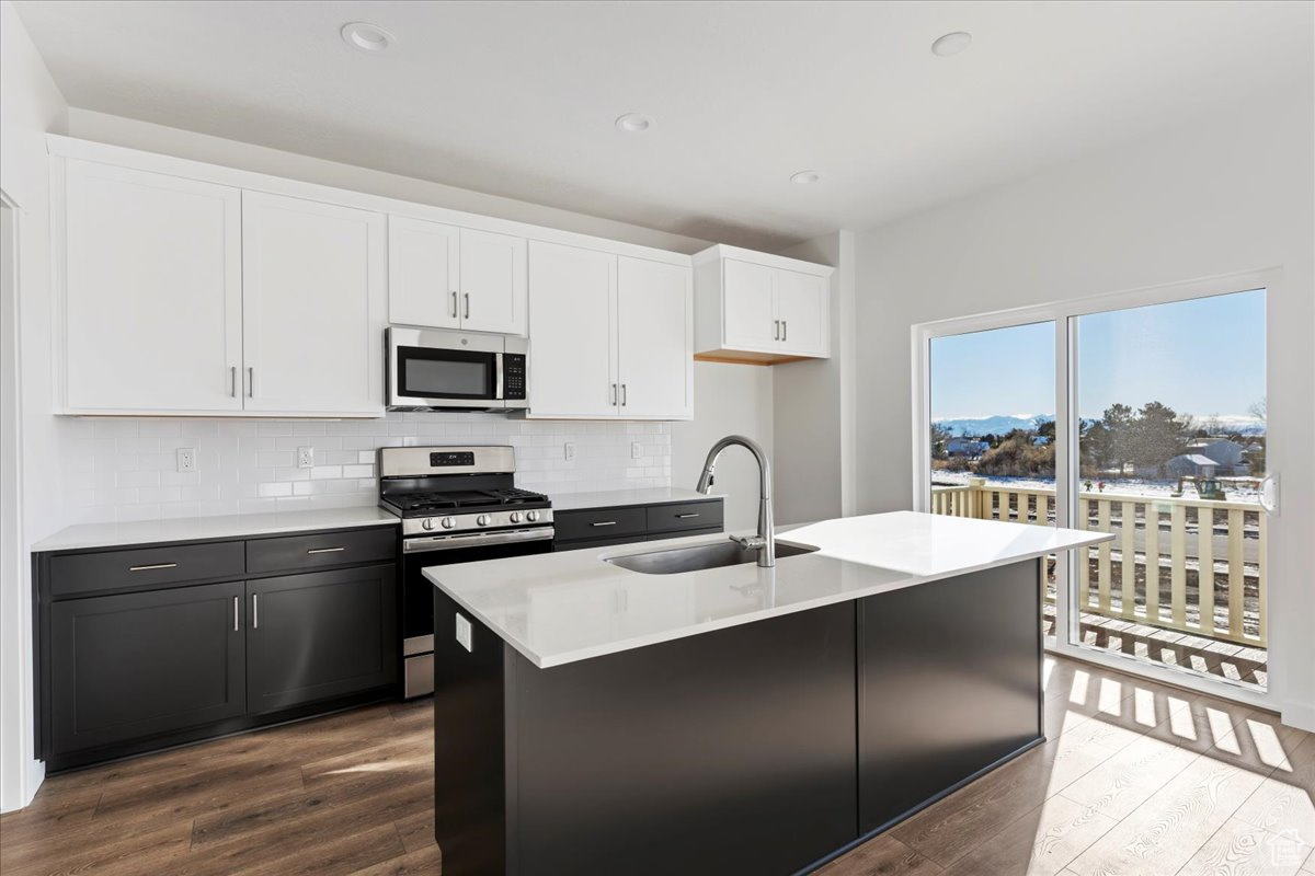 Kitchen with a kitchen island with sink, sink, white cabinets, and stainless steel appliances