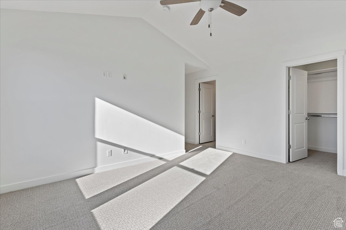 Interior space featuring ceiling fan, light colored carpet, and vaulted ceiling